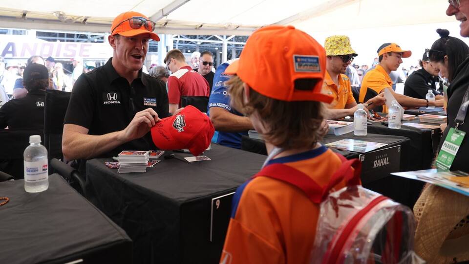 Scott Dixon signing an autograph for a child