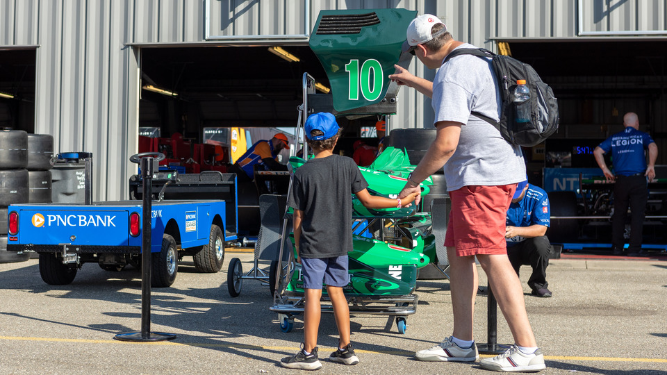 A father and son inspect a car in the Music City Grand Prix Garages.
