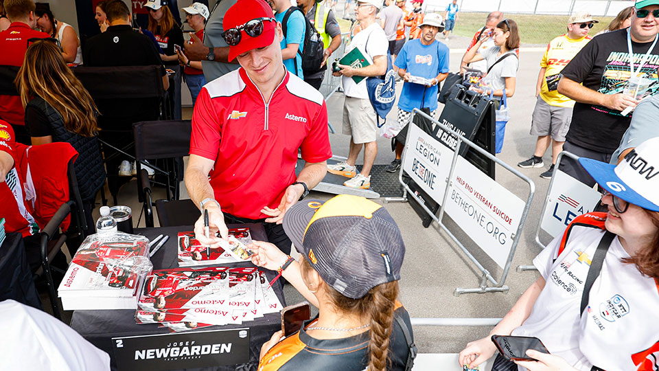 A child gets Josef Newgarden's autograph